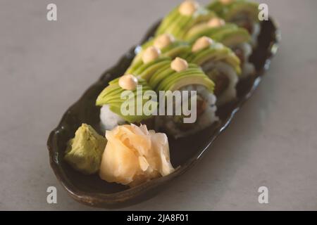 Rotolo di sushi di drago coperto con pezzi di avocado Foto Stock