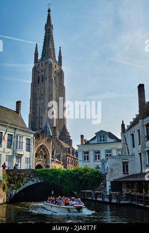 Bruges, BELGIO - 28 MAGGIO 2018: Barca turistica nel canale vicino alla Chiesa Di Nostra Signora . Brugge Bruges, Belgio Foto Stock