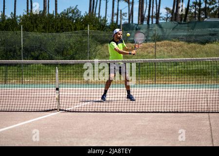 Giocatore di tennis che esegue un tiro di caduta sul campo. Foto Stock