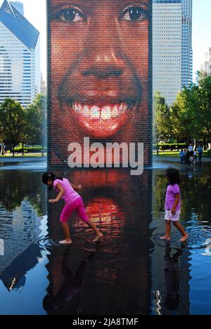 Due ragazze giocano nelle acque della Crown Fountain di Chicago mentre un video mostra i diversi volti della città Foto Stock