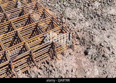 la rete di rinforzo del telaio ricoperta di ruggine giace sul terreno, in attesa di essere sollevata all'orizzonte di montaggio, fuoco selettivo Foto Stock