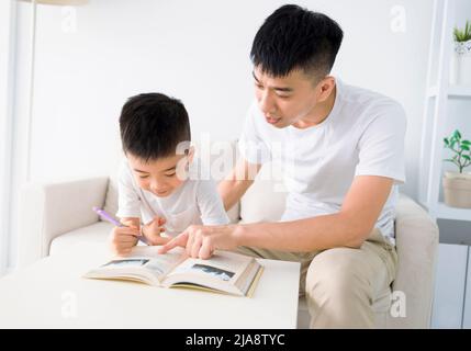 Padre che aiuta il figlio a fare i compiti a casa Foto Stock