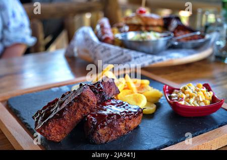 Costolette con patate fritte e insalata su tavola rustica Foto Stock