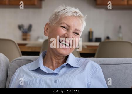 Signora anziana positiva con hairdo corto elegante ridere su scherzo Foto Stock
