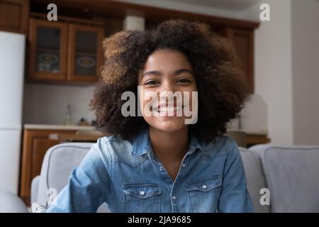 Giovane ragazza allegra donna nera seduta sul divano guardando la webcam Foto Stock