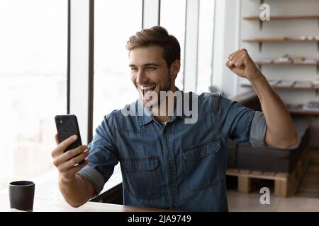 Uomo felice millenario in casual eccitato con buone notizie Foto Stock