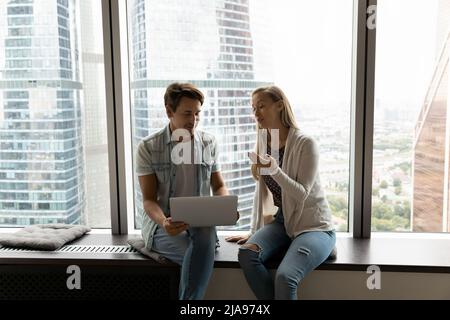 Due colleghi d'ufficio, i dipendenti che si incontrano, parlano alla grande finestra panoramica Foto Stock