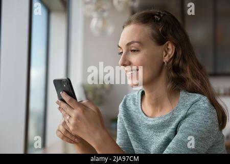 Ragazza sorridente felice usando il telefono cellulare, leggendo il testo Foto Stock