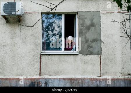 Una donna anziana fissa la finestra a Lysychansík, nella regione di Luhansk. Lysychansk è una città situata sulla riva destra del fiume Donets, nella regione di Luhansk. La città fa parte di un'area metropolitana che include Severodonetsk e Rubizhne; le tre città costituiscono uno dei più grandi complessi chimici dell'Ucraina. Lysychansk è ora la prima linea da quando le truppe russe hanno distrutto il ponte che collega Severodonetsk a Lysychansk. Le truppe russe attaccano la città e si muovono verso di essa. L'esercito russo occupa la strada principale che collega Lysychansk a Kramatorsk. (Foto di Rick Mave/SOPA Images Foto Stock