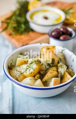 Insalata di patate con aneto e olive in una ciotola su sfondo blu. Cibo sano, vegano e ricette magre. Foto Stock