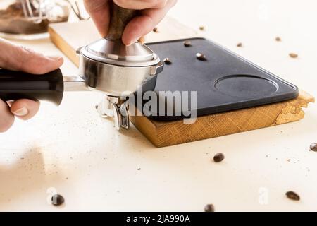 Il barista utilizza un manomissione per preparare il caffè. Foto Stock