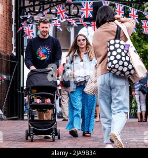 Epsom Surrey, Londra UK, 28 2022 maggio, giovani coppie a piedi spingendo Un passeggino bambino attraverso Market Square Foto Stock