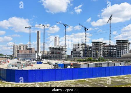 Lunghi pannelli di rivestimento in legno blu senza marcatura che racchiudono nuovi lavori di costruzione di edifici in corso su un alto condominio di appartamenti oltre East London UK Foto Stock