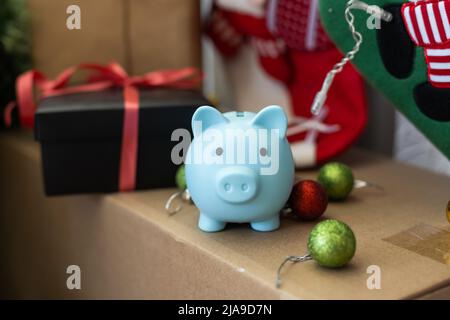 Sotto l'albero di Natale sono scatole con i regali. Sulla scatola c'è una piccola banca di porcellini. Bella carta festiva. Foto Stock