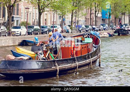 Uomo e donna, coppia, abbracciano viaggiare in una chiatta, barca, lungo un canale alberato della città di Amsterdam. Foto Stock