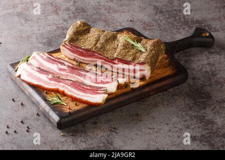 Delizioso piatto artigianale intero affumicato pancetta closeup sul bordo di legno sul tavolo. Orizzontale Foto Stock