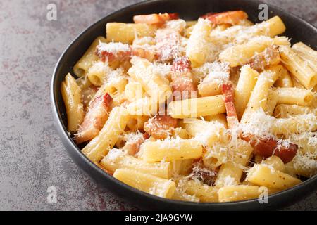 Pasta alla Gricia Pasta tipica italiana con pecorino e guanciale in primo piano nel piatto sul tavolo. Orizzontale Foto Stock