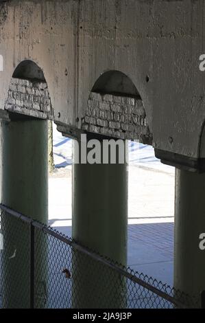 Colonnato industriale della città interna di colonne in cemento che reggono un ponte. Foto Stock