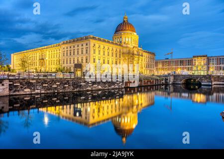 L'imponente palazzo della città ricostruito di Berlino di notte si riflette in un piccolo canale Foto Stock