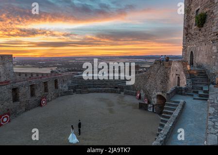 Una coppia nuziale che si prepara per un photoshoot nel mezzo dell'arena del castello di Monsaraz al tramonto, Alentejo, Portogallo. Foto Stock