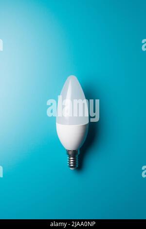 Lampadina moderna a risparmio energetico su sfondo blu, immagine concettuale con spazio di copia Foto Stock