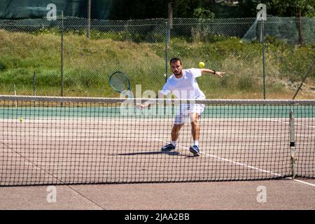 Giocatore di tennis che esegue un tiro di caduta sul campo. Foto Stock