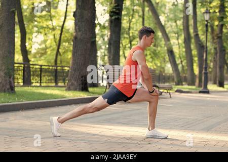 L'uomo atletico tiene la posizione di affondo. Allungamento delle gambe post-allenamento. Routine di allungamento Foto Stock