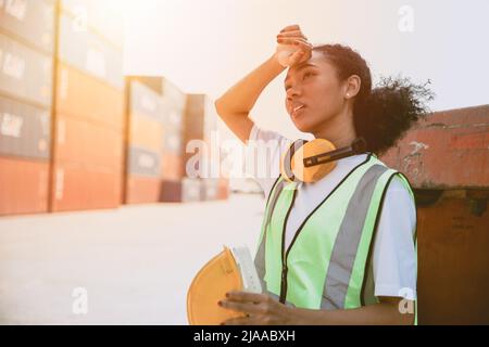 lavoratrice donna lavoro duro. nero ragazza personale stanco lavoro nel porto contenitore. teen signora lavoro in zona di pericolo. lavoro giovane dipendente. Foto Stock