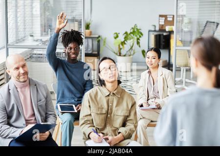 Ritratto di giovane uomo nero alzando la mano facendo domanda durante il seminario educativo in ufficio, spazio copia Foto Stock