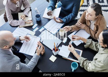Vista dall'alto in un gruppo di persone diverse al tavolo di riunione in ufficio ambiente comunicante e gesturante Foto Stock