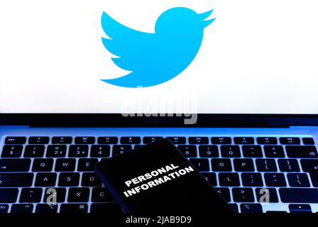 Parole INFORMAZIONI PERSONALI visualizzate sullo smartphone e logo Twitter su un notebook sfocato dietro di esso. Concetto. Stafford, Regno Unito, 29 maggio 2022 Foto Stock