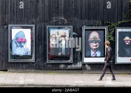 Bristol, Regno Unito. 28th maggio 2022. Un membro del pubblico cammina accanto a una serie di poster incorniciati e iconici su North Street, Bedminster, Bristol Foto Stock