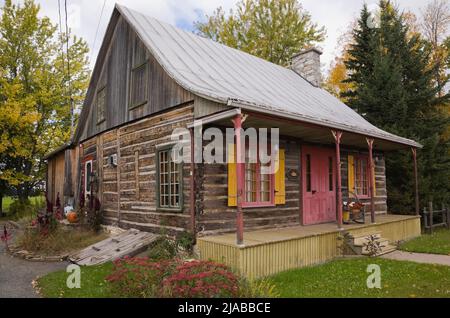 Vecchio circa 1825 Canadiana casetta stile casa di tronchi con lamiera zincata tetto in autunno. Foto Stock