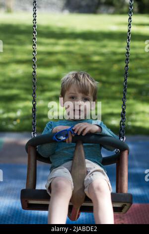 Il ragazzo di 3 anni gioca su un'altalena in un parco Foto Stock