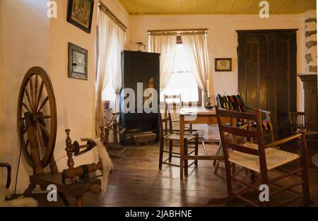 Ruota rotante e mobili antichi in soggiorno all'interno del vecchio circa 1840 Canadiana cottage stile fieldstone casa. Foto Stock