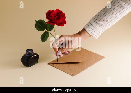 Set vintage creativo di penna stilografica, inkpot, rosa rossa in fiore e busta. Business o romantico concetto minimo. Foto Stock