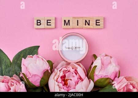 Composizione piatta con bellissimi fiori e confezione regalo con anello di aggancio. Sono miei cubetti di legno con iscrizione. Foto Stock