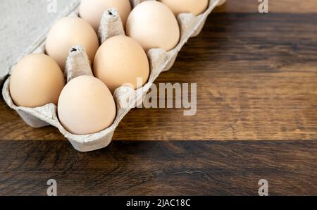 Dieci uova di pollo in un vassoio di cartone sul tavolo. Foto Stock