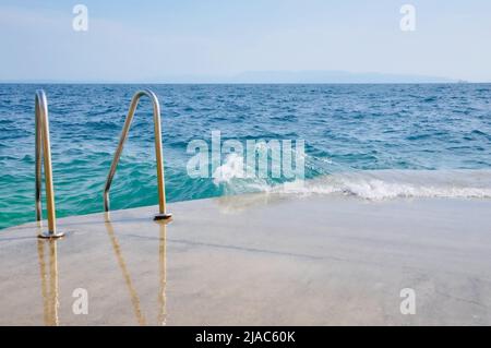 Scale per il mare. Scala in metallo con corrimano al mare. Scala di metallo conduce al mare. Scala che conduce al mare. Estate foschia Foto Stock