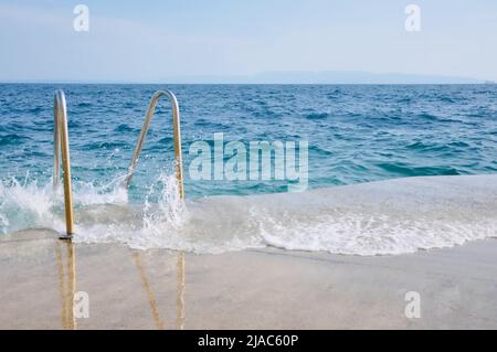 Scale per il mare. Scala in metallo con corrimano al mare. Scala di metallo conduce al mare. Scala che conduce al mare. Estate foschia Foto Stock