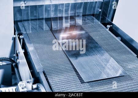 Background industriale. Nastro trasportatore della macchina per la formatura di lamiere in fabbrica. Produzione di tegole, primo piano, lavorazione industriale dei metalli Foto Stock