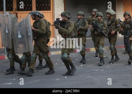 Hebron. 29th maggio 2022. I soldati israeliani sono visti a seguito di una protesta contro la marcia della bandiera nella città di Hebron, in Cisgiordania, il 29 maggio 2022. La controversa marcia di bandiera organizzata dai gruppi di estrema destra israeliani si svolgerà domenica in occasione della Giornata di Gerusalemme, che commemora l'unificazione della città dopo che Israele annessa Gerusalemme Est nel 1967. Il suo percorso è programmato per passare dalla porta di Damasco e il quartiere islamico nella città vecchia. Credit: Mamoun Wazwaz/Xinhua/Alamy Live News Foto Stock