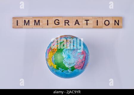 Parola immigrazione scritto su cubi di legno e mondo. Vista dall'alto. Foto Stock