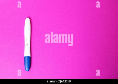Test di gravidanza positivo su sfondo rosa. Spazio di copia Foto Stock