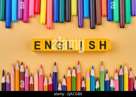 La parola INGLESE scritto su cubi di plastica in cornice da forniture scolastiche colorate. Composizione della disposizione piatta. Foto Stock
