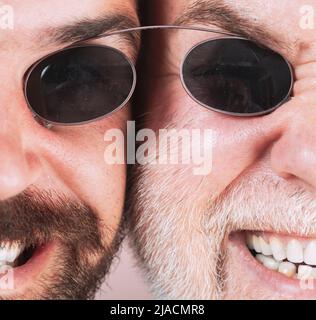 Occhiali da uomo. Due Beardeds di mezza età indossano occhiali guardando la fotocamera con una espressione seria. Concetto di occhiali. Uomo anziano con figlio. Foto Stock
