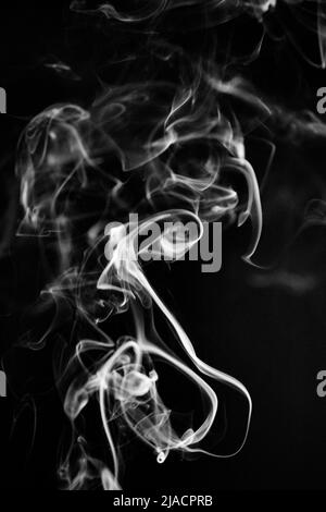 Un modello di fumo bianco, vorticoso, ascendente su uno sfondo nero, la foto potrebbe essere usata come sfondo, trama di fumo o astratto, o pho di stock generale Foto Stock