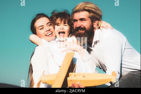 Abbraccio felice famiglia abbracciare all'aperto. Famiglia allegra divertirsi all'aria aperta. Bambino che gioca con madre e padre e divertirsi. Figlio che abbraccia i genitori Foto Stock