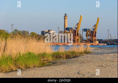 Gru portuali e un faro a Swinoujscie in Polonia in un pomeriggio di sole Foto Stock