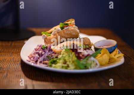 Primo piano di panini con pollo, brie e insalata con insalata di coleslaw, insalata verde e patatine Foto Stock